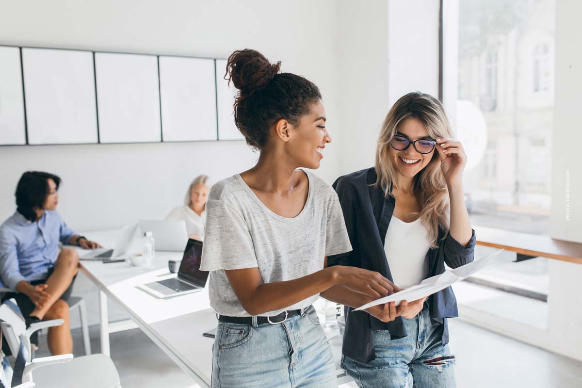 young-female-executive-explaines-new-strategy-blonde-employee-glasses-smiling-indoor-portrait-multicultural-collective-working-project-office-using-laptop